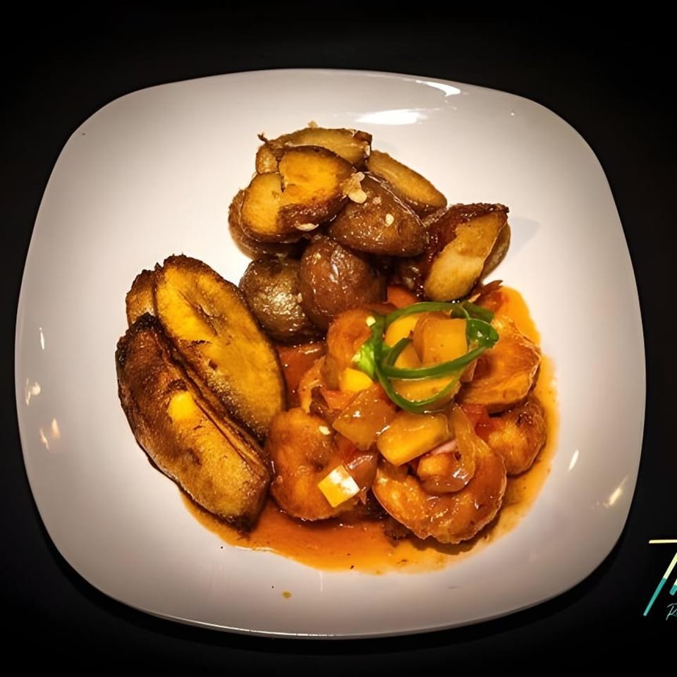 Caribbean dish with fried plantains, roasted potatoes, and shrimp in a sweet sauce.