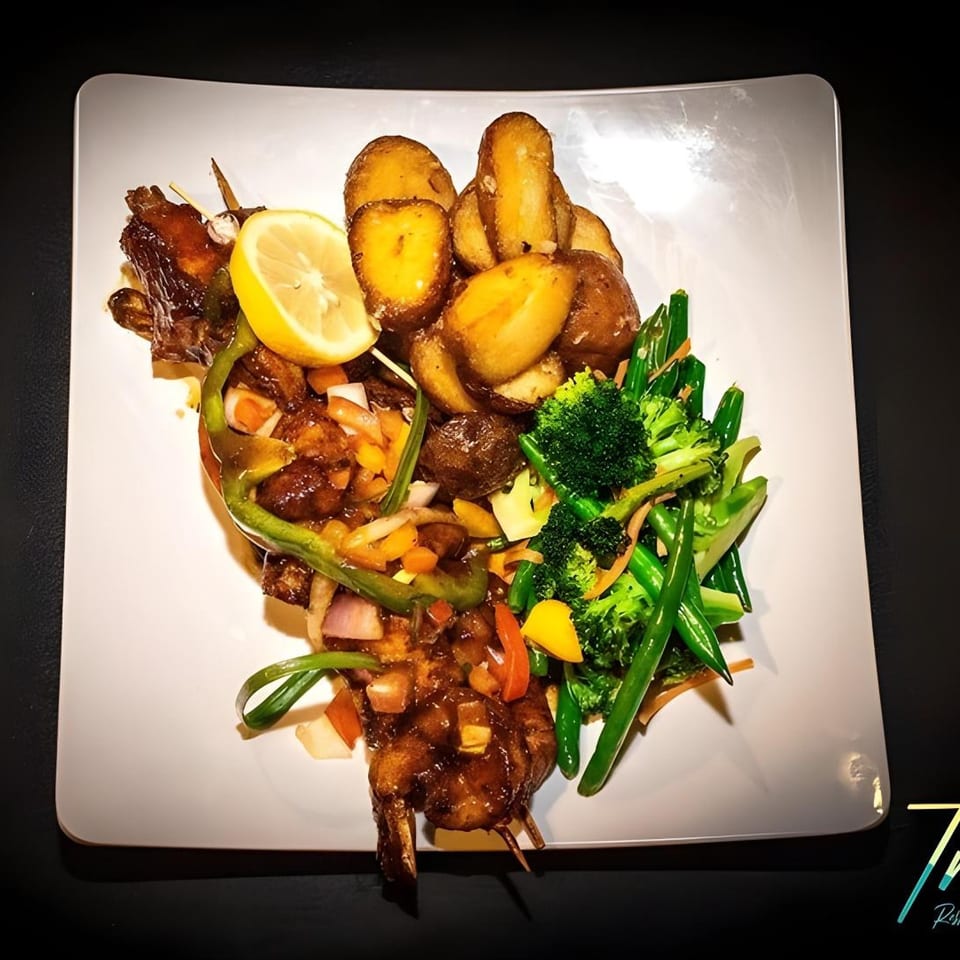 Truth Restaurant's Caribbean dish with shrimp skewers, roasted potatoes, and steamed vegetables.